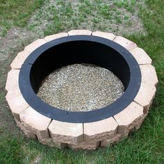 an outdoor fire pit in the grass with gravel around it's edges and bottom