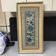 a framed art piece sitting on top of a counter