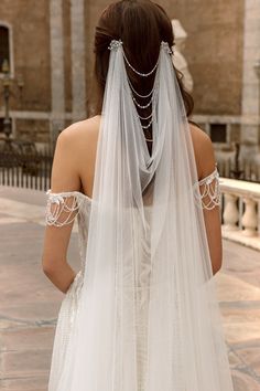 the back of a bride's wedding dress, with veil draped over her shoulder