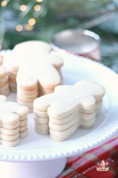 some cookies are on a white plate near a christmas tree