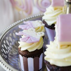 some cupcakes with icing and decorations on a silver platter for dessert