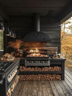 an outdoor kitchen with wood logs on the floor and a stove in the center,