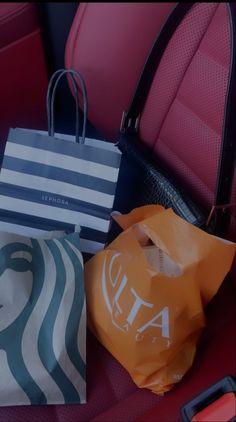 three shopping bags sitting on top of a red chair