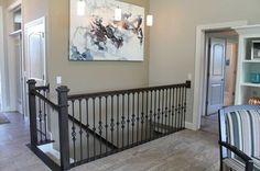 a living room filled with furniture and a painting hanging on the wall above it's railing