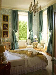 a bedroom with a bed, chandelier and two windows