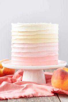 a layered cake with peaches on the side and white frosting, sitting on top of a wooden table