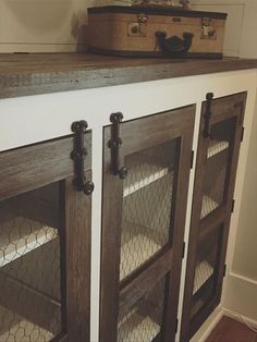 an old suitcase is sitting on top of a cabinet with chicken wire in the doors