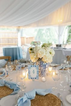 the table is set with blue and white plates, silverware, and flowers in a vase