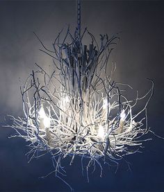 a white chandelier with branches hanging from it's sides and lights on