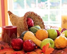 a table topped with apples, oranges and other fall foods next to a window