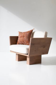 a wooden chair with two pillows on it's back and one seat up against the wall