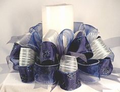 a blue and silver wreath with a candle on the top is sitting next to a white pillar