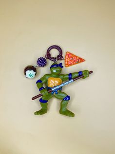 a keychain with a teenage mutant holding a pizza slice and a baseball bat