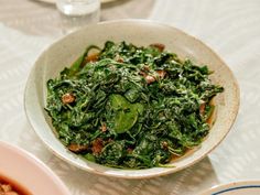 a white bowl filled with greens on top of a table