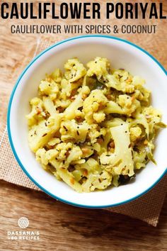 cauliflower with spices and coconut in a white bowl on a wooden table top