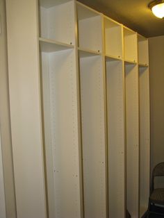 an empty room with several shelves and a chair next to it in front of the wall