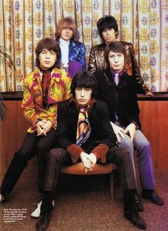 the rolling stones posing for a photo in front of a colorful wallpapered background