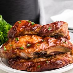 two ribs covered in bbq sauce and garnished with parsley on a white plate