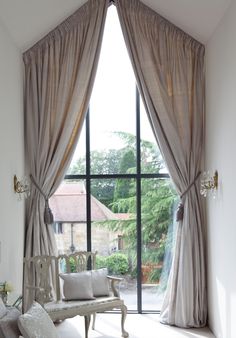 a living room filled with furniture and a large window covered in curtained drapes