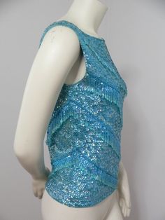 Lovely aqua sequinned and beaded shell from the late 50's. It is wool and made in Hong Kong. Covered in aqua sequins with diagonal rows of beaded dangles. It is unlined with a long back metal zipper for closure. Shown on form with 34.5 inch bust and 25.5 inch waist. Size tag says 38. Measurements flat are bust and waist 16 inches cross and 21 inches. Condition is good with a few beads missing at one shoulder where there are loose threads. Not sure why but the inside wool is faded in the shape of Blue Beaded Fitted Sequin Fabric, Blue Beaded Sequin Fabric, Fitted Blue Beaded Sequin Fabric, Beaded Shell, Peep Toe Shoes, Needle Lace, Spring Fling, Shell Beads, Metal Zipper