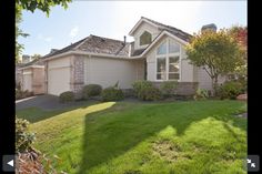 a house that is in the middle of a yard with grass and bushes around it