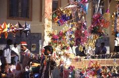 people are looking at items on display in front of a building that has been decorated with colorful ribbons and streamers