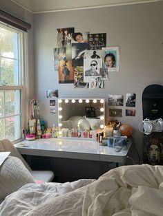 a bedroom with a bed, desk and pictures on the wall above it's mirror