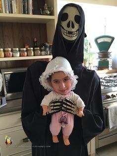 a woman in a nun costume holding a baby doll with a skeleton on it's head