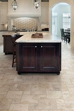 a large kitchen with an island in the middle and two chandeliers hanging from the ceiling