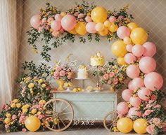 a table topped with balloons and flowers next to a cart filled with cake on top of it