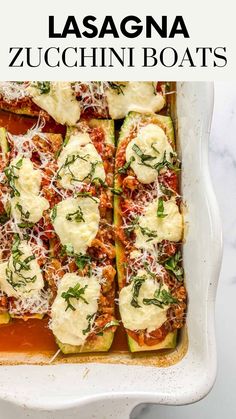 zucchini boats in a white casserole dish topped with cheese and herbs