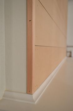 the corner of a room with a white wall and wood paneling on the floor