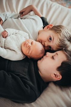 two young boys laying next to each other on top of a bed