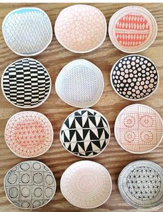 nine plates with different designs on them sitting on a wooden table in front of a wall