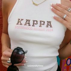 a woman wearing sunglasses and a tank top with the word kappa on it