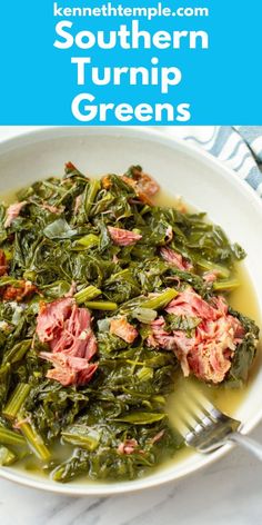 a white bowl filled with greens and meat on top of a marble table next to a fork