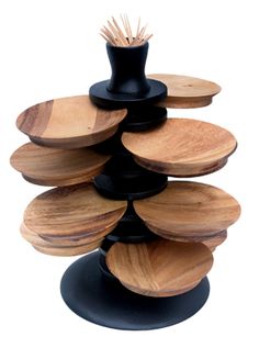 a stack of wooden plates sitting on top of a black stand with a plant in it