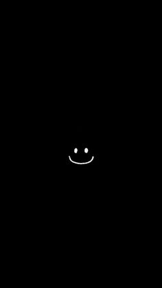 a black background with a smiley face drawn in the center and two white dots at the bottom