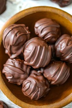 a wooden bowl filled with chocolate candies on top of a white table next to cookies