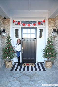 a woman standing in front of a door with christmas decorations on the outside and inside