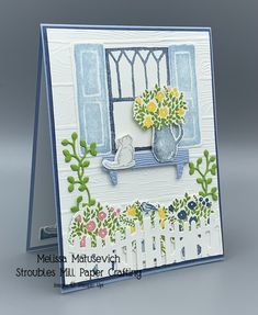 a card with flowers and a window on the outside, in front of a gray background