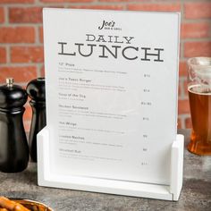 a menu sitting on top of a table next to a plate of food and a glass of beer