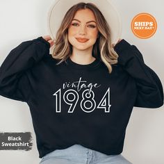 Our handmade 1984 sweatshirts are crafted from the highest quality materials for an ultra-soft and comfortable wear. Our trendy Birth year hoodies ship the same or next business day and are printed using an eco friendly water based ink that is not only safe for you but also safe for the environment! 💖  Bold and Bloom Co. offers trendy items for any occasion! Our shirts are crafted from the highest quality materials for ultra-soft and comfortable wear. Most importantly, all of our items are printed using the most advanced apparel printer to ensure vibrant colors and detailed graphics.  📝 PRODUCT DETAILS  - The sleeves are rolled up for display purposes only. -Here's what it says for the materials Materials:  Sweatshirts fabric: 50/50 cotton poly blend Unisex Short Sleeve fabric:  white, b Casual Black Sweatshirt For Birthday, Black Casual Sweatshirt, Black Long Sleeve Sweatshirt For Birthday, Black Graphic Print Sweatshirt For Birthday, Black Crew Neck Sweatshirt For Birthday, Matching Birthday Outfits, Year Sweatshirt, Trendy Items, Comfort Colors Tshirt