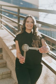 a woman holding a large metal object in her hands while standing on the steps outside