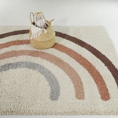 a rug with a basket on top of it next to a stuffed animal in the middle