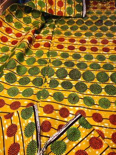 an african print fabric with circles and dots in yellow, green, red and black