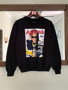 a black sweatshirt hanging on a mirror with an advertiser's face printed on it