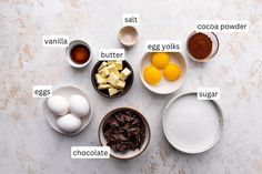 ingredients for chocolate cake laid out in bowls on a white surface with words describing the ingredients