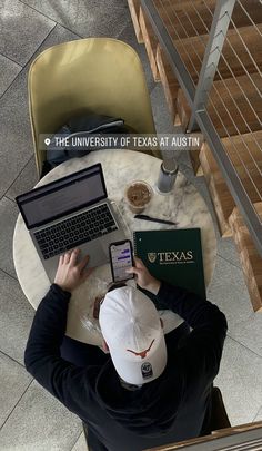 a man sitting at a table with two laptops and a phone in front of him