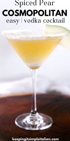 a close up of a drink in a glass on a table with the text spiced pear cosmopolian easy vodka cocktail